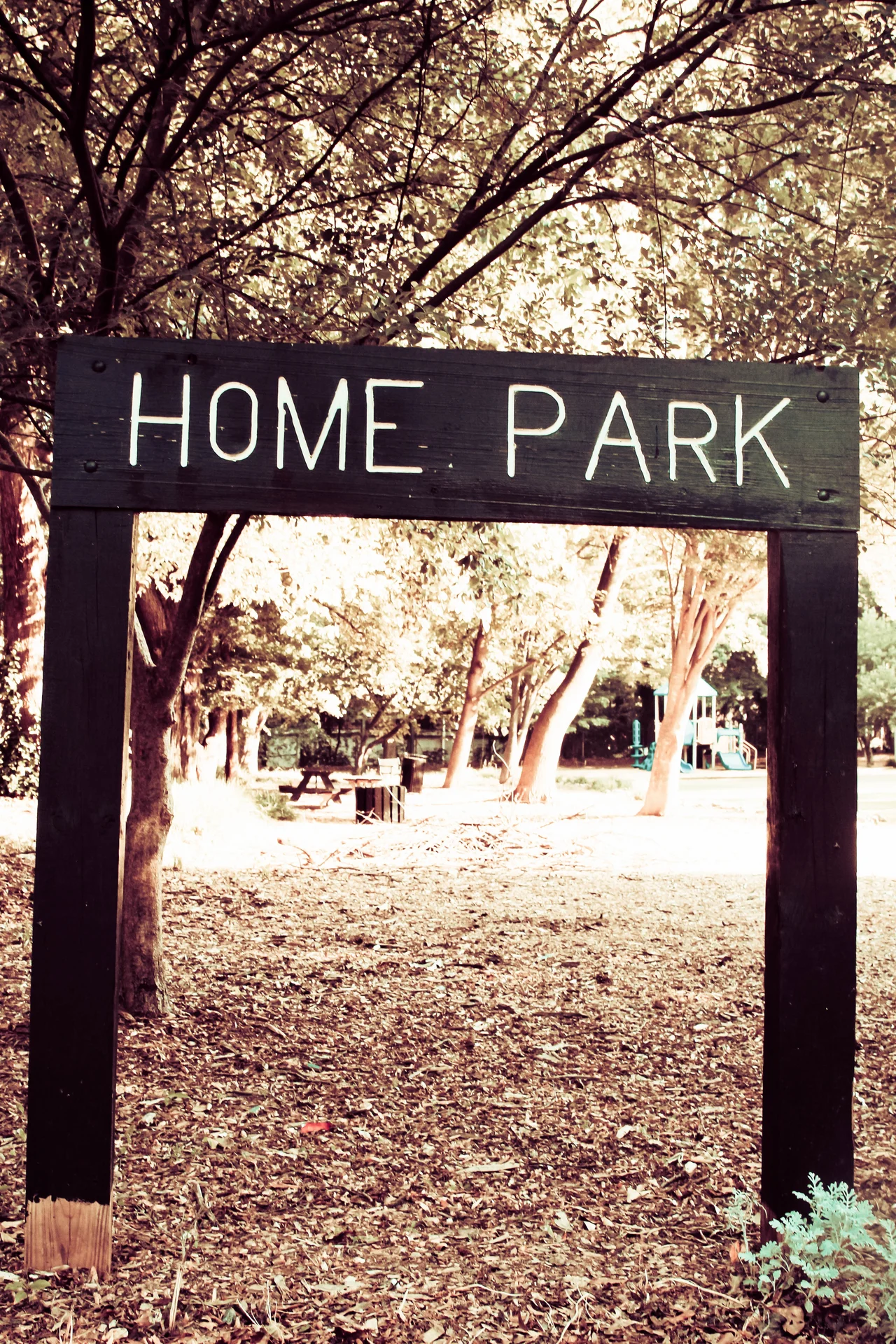 A wooden Home Park sign frames a tree-shaded park entrance in Atlanta.